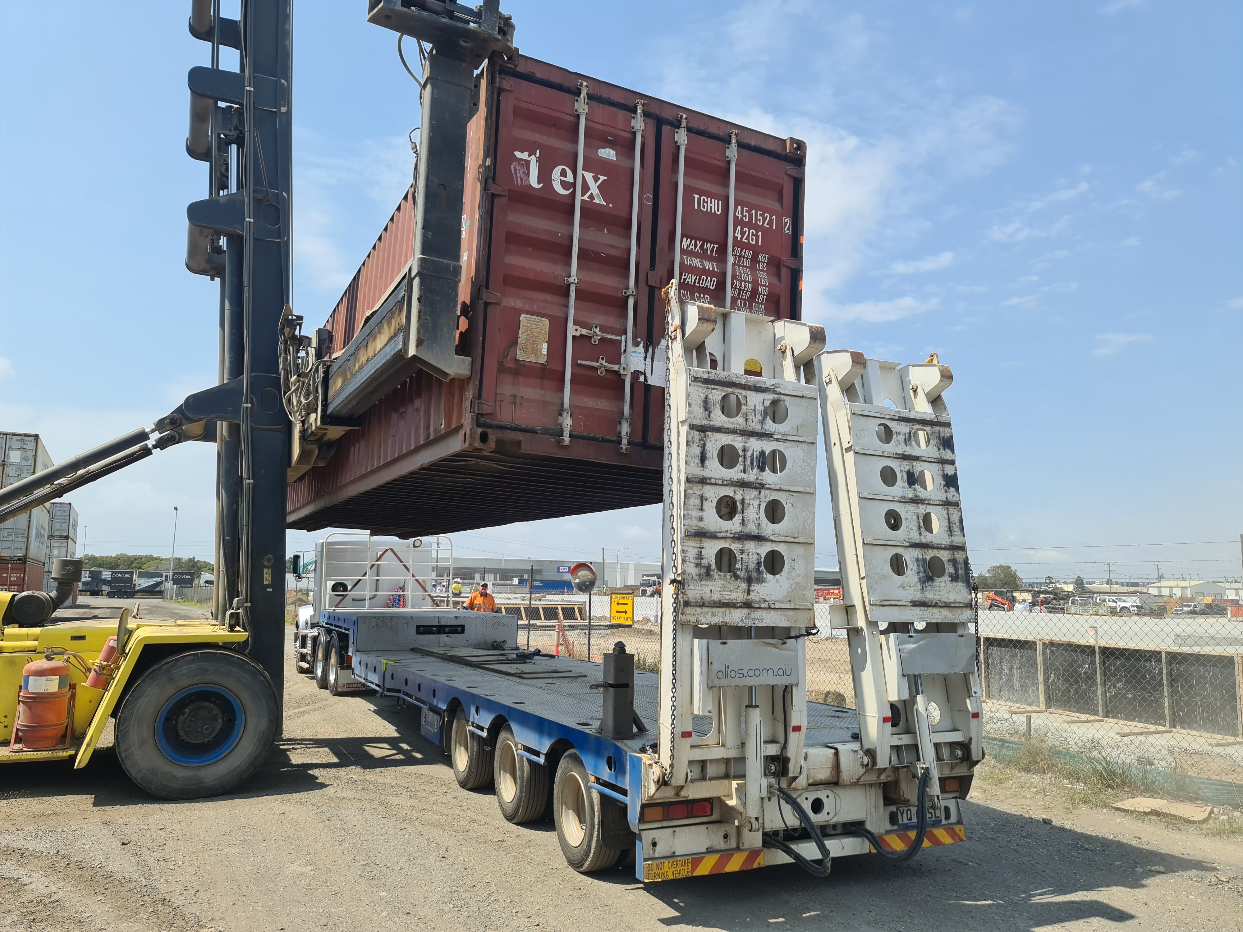 A shipping container being loaded onto a truck